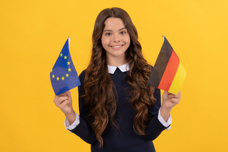 happy kid hold european union and german flag yellow background, germanyの写真素材