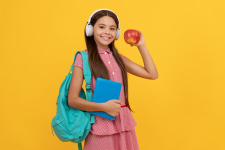 back to school. knowledge day. concept of education. kid in headphones with workbook and appleの写真素材