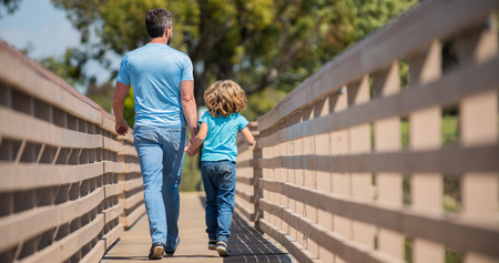 parenting and fatherhood. fathers day. happy father and son walking outdoor back view.の写真素材