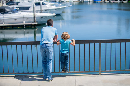 father and son relax looking at yachts in harbor, family weekendの写真素材