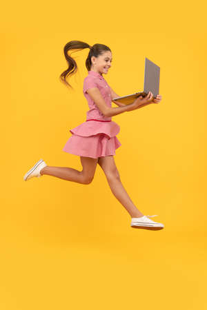 It is bargain. child jump with computer. happy kid play game on notebook. just have fun.の写真素材