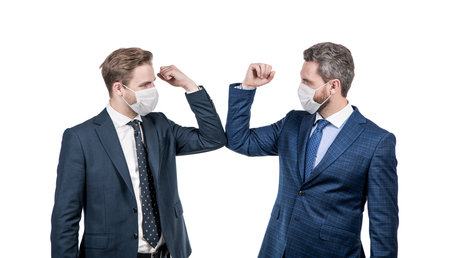 businessmen in mask bumping elbows instead of shaking hands to avoid contact, business greeting.の写真素材