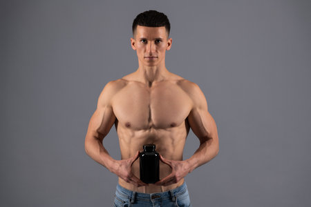 Sports nutrition product. Shirtless guy hold nutritional supplements. Dietary supplementsの写真素材