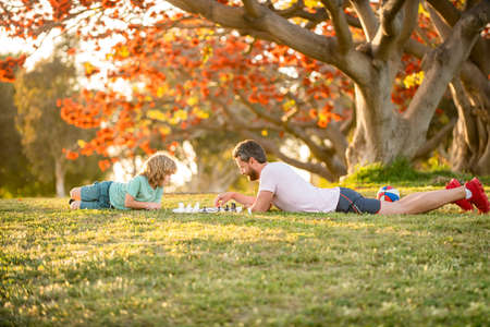 happy family of daddy and son child playing chess on green grass in park outdoor, togethernessの写真素材