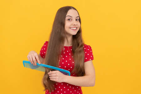 female fashion model. happy kid combing long hair. hairdresser. girl has wavy hairdoの写真素材