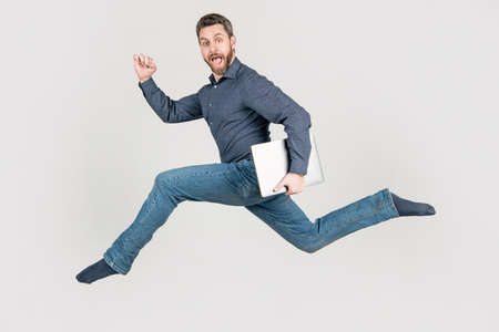 energetic man businessman running while working online on laptop hurry up for shopping, motion.の写真素材