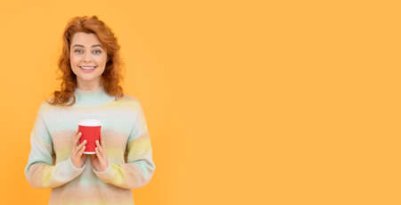 happy redhead woman drink takeaway coffee from cup on yellow background, copy space, morningの写真素材