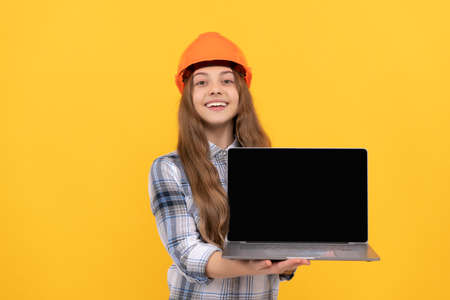 happy teen girl in helmet and checkered shirt presenting computer, presentationの写真素材