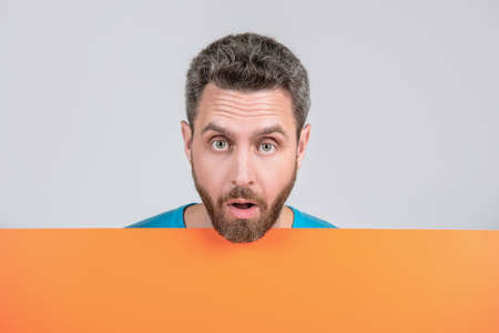 surprised mature bearded man behind orange black paper banner with copy space for info, salespersonの写真素材