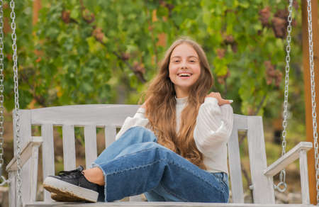 glad teen girl having free time outside on swing, playgroundの写真素材