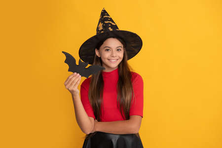 smiling kid with bat wearing witch hat on yellow background, halloweenの写真素材