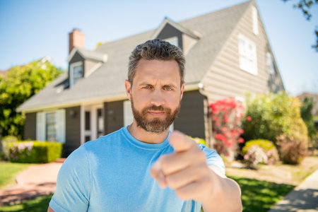 mature man standing outdoor at house pointing finger on camera, rentalの写真素材
