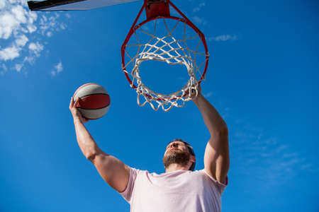 muscular man player throw basketball ball through basket, male basketballの写真素材