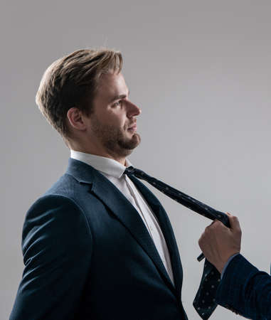 Professional employee man being pulled by necktie during workplace fight grey background, conflictの写真素材