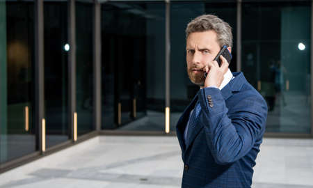 mature business man in formalwear talking on phone outdoor, copy space, negotiationの写真素材