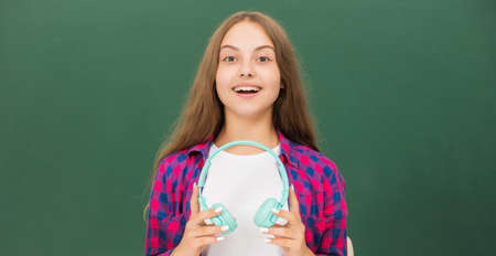 happy kid with earphones at blackboard, musicの写真素材