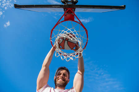 happy man with basketball ball on court. professional basketball player training outdoorの写真素材