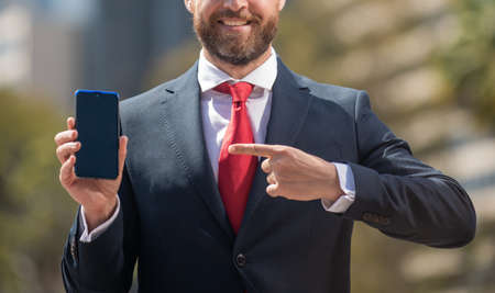 bearded businessperson in formalwear pointing finger on phone outside the office, cyber mondayの写真素材