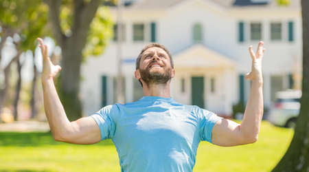 happy unshaven guy standing near new house celebrating success, new home