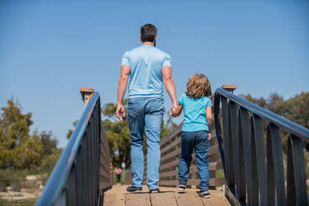 single dad leading small child outside back view, childhood