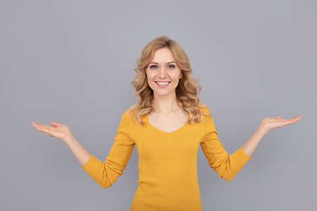 blonde woman presenting product. blond woman portrait. express positive emotions.の写真素材