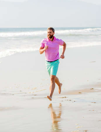 sporty man runner sprinting on beach outdoor, summer