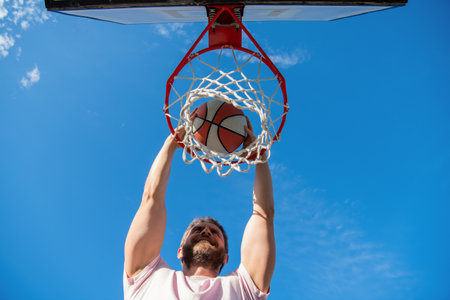 cheerful man player throw basketball ball through basket, motivation
