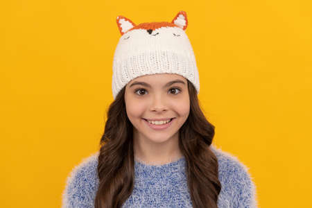 happy child in sweater and hat on yellow background, winterの写真素材