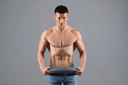 Bodybuilder do muscle building workout with resistance band grey background, trainingの写真素材