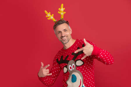 happy man in winter sweater and party antlers. xmas guy on red background. happy new year.の写真素材