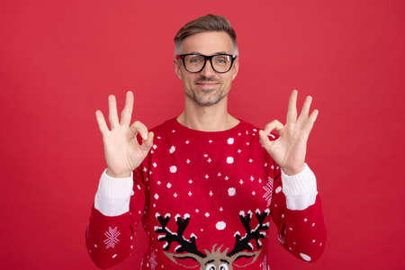 happy man in winter sweater and glasses. xmas guy on red background. happy new year.の写真素材