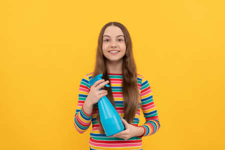 Happy kid hold disinfectant spray product in bottle for copy space yellow background, disinfectionの写真素材