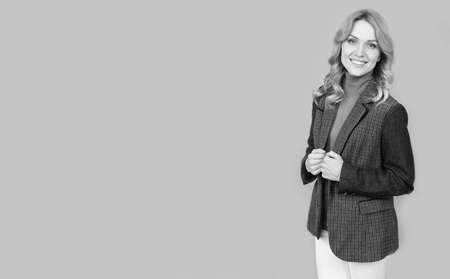 cheerful blonde businesswoman in british jacket on grey background, copy space, fashion.の写真素材