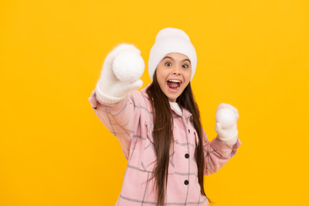 playing snowballs. winter activity. amazed kid in hat. teen girl in mittens with decorative ballの写真素材