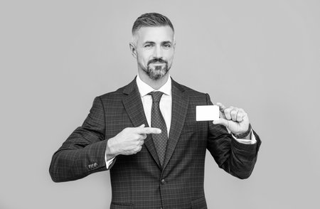 confident businessman man in suit pointing finger on business card for copy space, contact meの写真素材