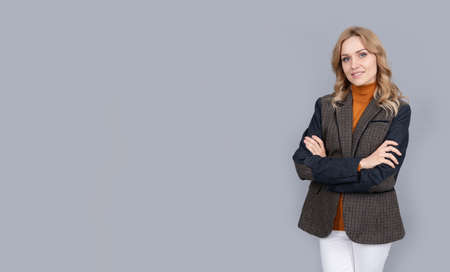 cheerful blonde businesswoman in british jacket on grey background, copy space, style.の写真素材