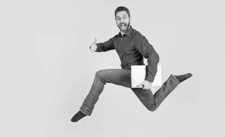 jumping man running while working online on laptop hurry up for shopping show thumb up, success.