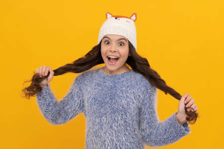 winter fashion. amazed happy kid with curly hair in hat. female fashion model. teen girlの写真素材