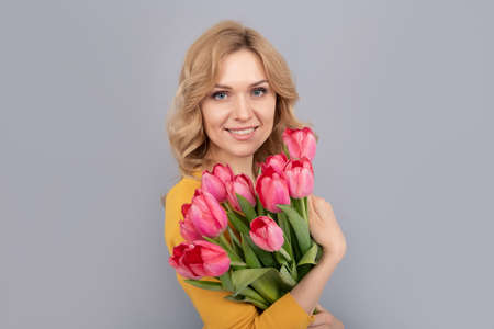 smiling woman with tulips. lady hold flowers for spring holiday. girl with bouquetの写真素材