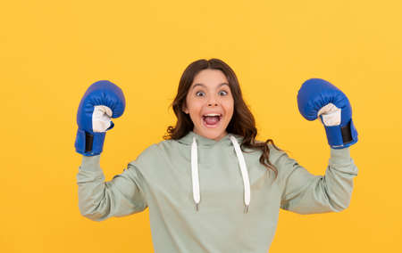 surprised child in boxing gloves on yellow background