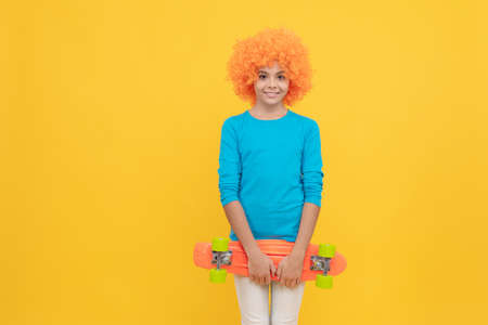 cheerful selfish child girl in curly wig hold penny board, copy space, childhoodの写真素材