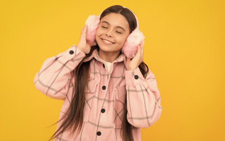 Warmth to touch. Happy child enjoy warmth of fur earmuffs. Fashion winter accessoriesの写真素材
