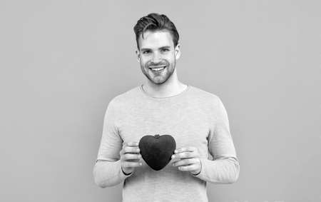My heart for you. Handsome guy smile holding red heart. Happy Valentines dayの写真素材
