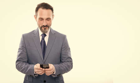 smiling grizzled ceo texting on smartphone isolated on white copy space, business communication.