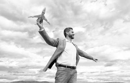 confident happy man businessperson in jacket hold toy plane on sky background, business successの写真素材