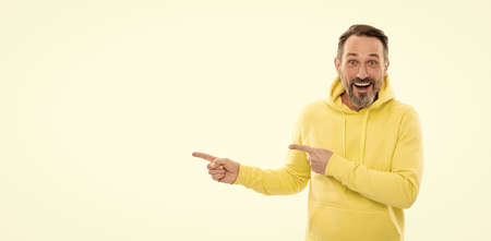 smiling senior guy presenting product isolated on white. advisor man in yellow hoody.