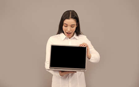 surprised woman in white shirt showing computer ad presentation, copy space, advert
