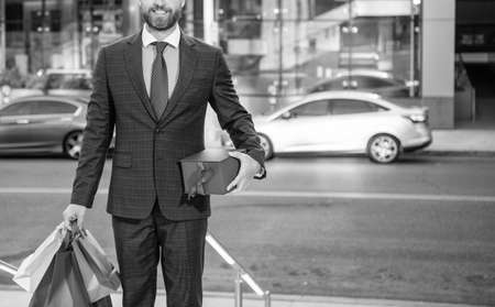 cropped entrepreneur in suit with shopping bags gifts walk outside the office, business reward.の写真素材