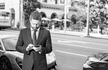 confident manager rent online. handsome businessman chatting on smartphoneの写真素材