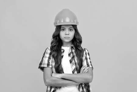 serious child with curly hair in construction helmet, builderの写真素材